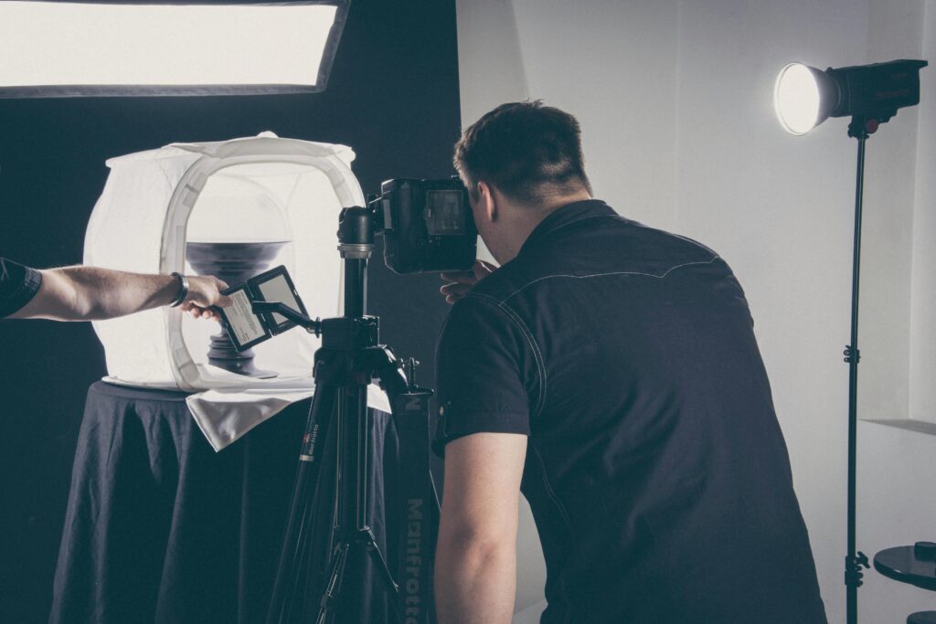 Photographer capturing product in a studio setup with lighting gear and camera.